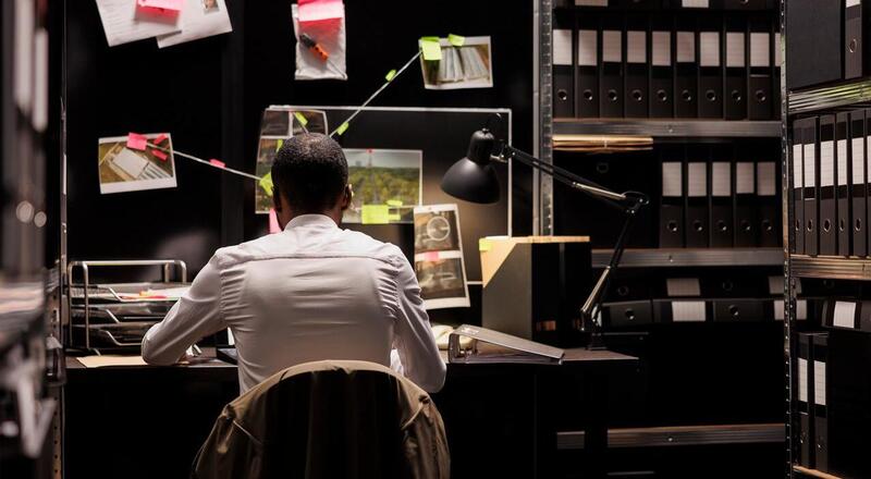 Detective analyzing evidence scheme hanging on wall